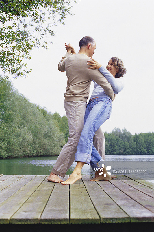 一对情侣在湖边的码头上跳舞图片素材