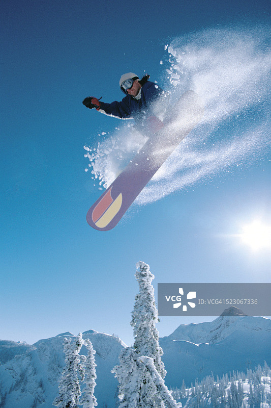 一个人在阳光明媚的日子里单板滑雪图片素材
