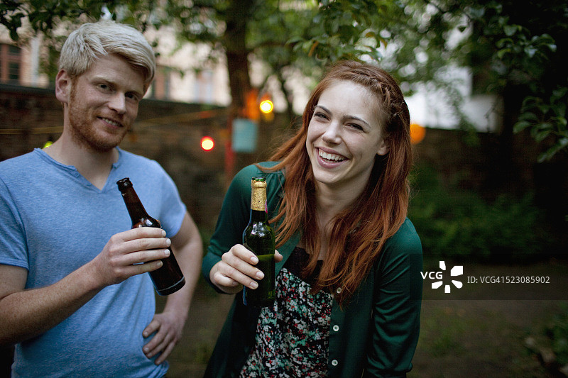 年轻的女人和年轻的男人在花园聚会上喝啤酒图片素材