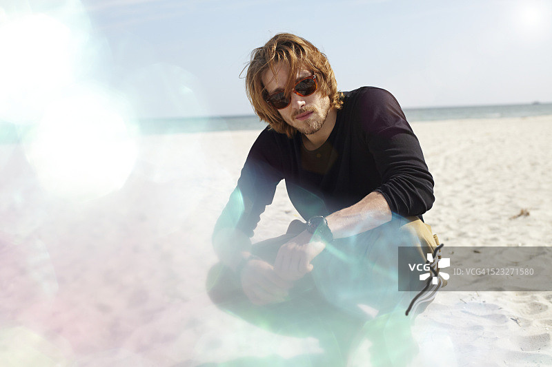 一个蜷伏在阳光沙滩上的男人的肖像图片素材