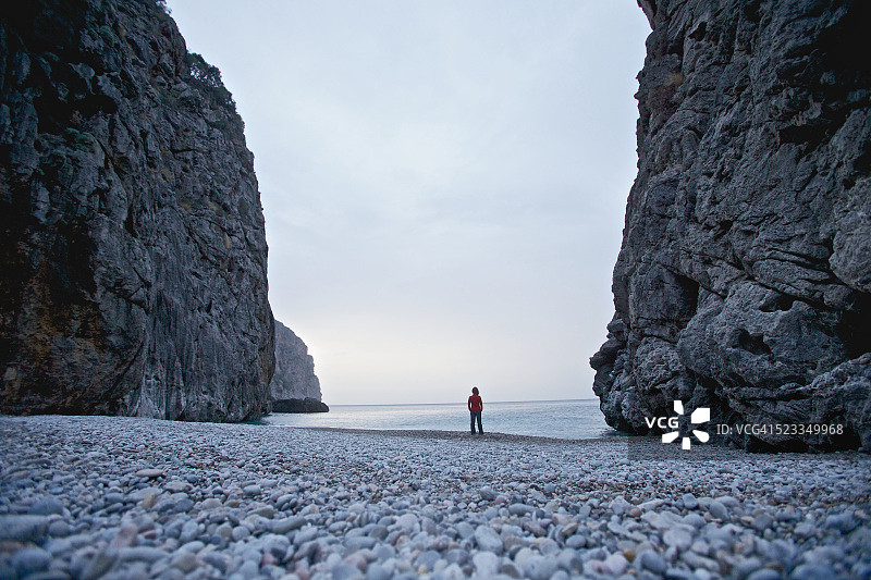 西班牙巴利阿里群岛，马略卡岛，一名年轻女子站在海上的两块岩石之间图片素材