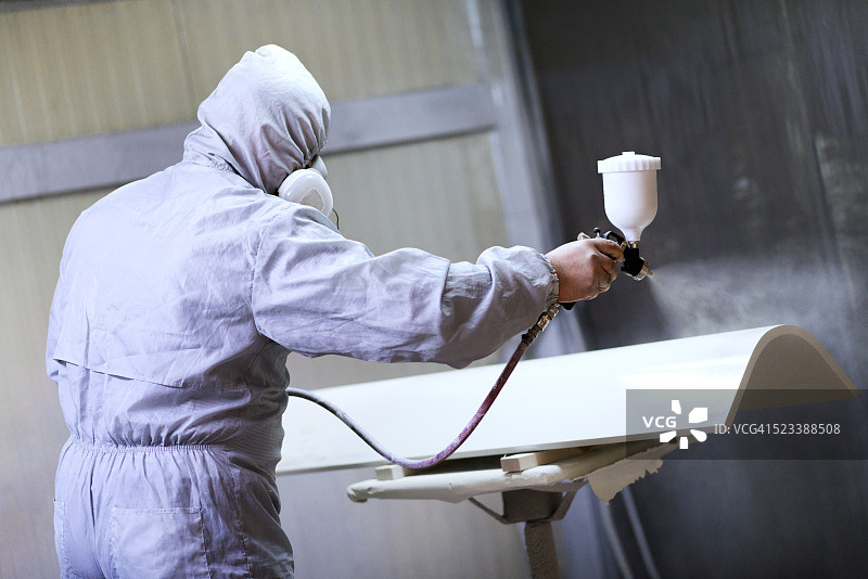 喷漆室的机械师为家具的木制部分喷漆图片素材