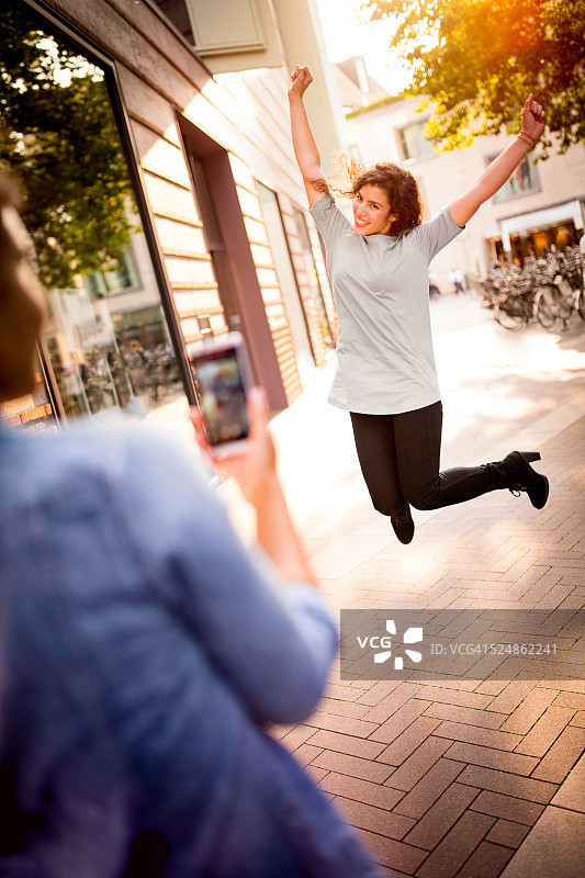 年轻女子拍下朋友在街上跳的照片图片素材