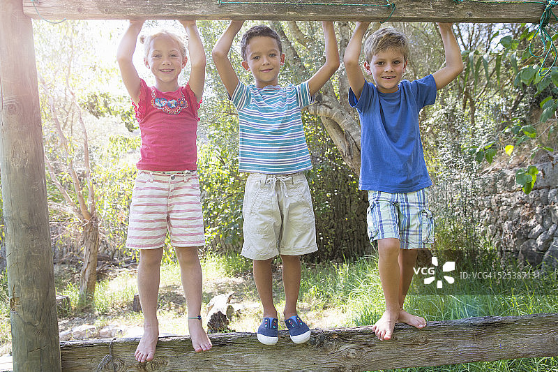 三个孩子站在花园的篱笆上图片素材