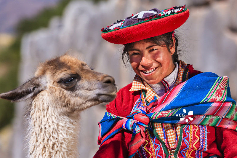 身穿民族服装的秘鲁女孩与美洲驼在库斯科附近摆姿势图片素材