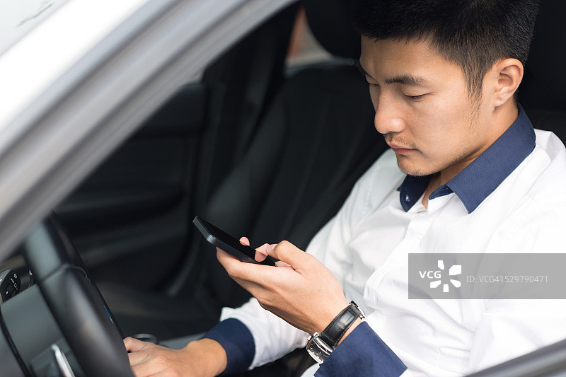亚洲年轻商人在车里使用智能手机图片素材