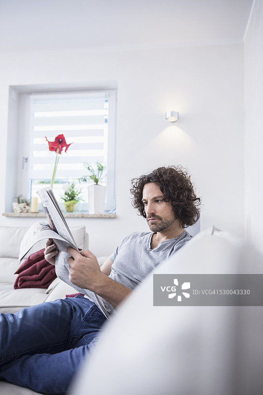 德国巴伐利亚慕尼黑，一名男子坐在沙发上看报纸图片素材
