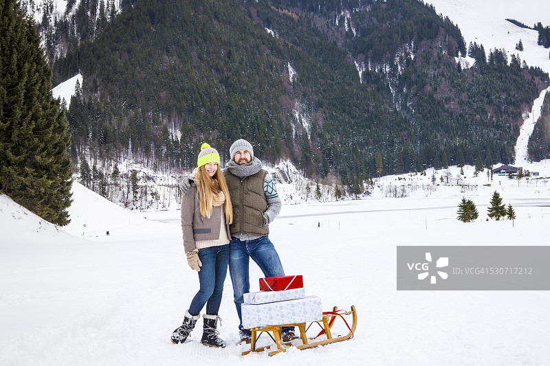 一对夫妇在雪橇上拉礼物，斯皮津湖，德国巴伐利亚图片素材