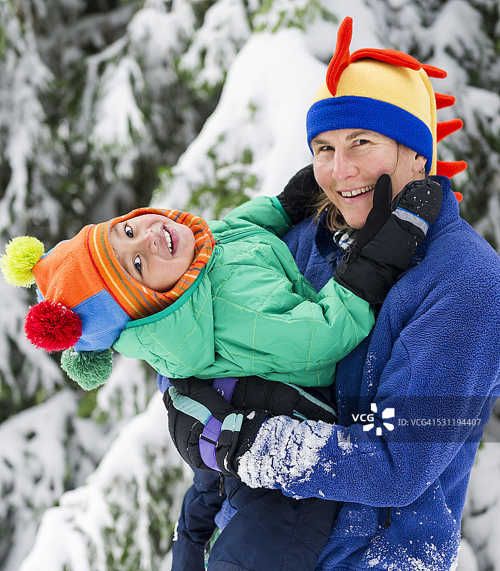 色彩鲜艳的妈妈和儿子正在享受今年的第一场雪图片素材
