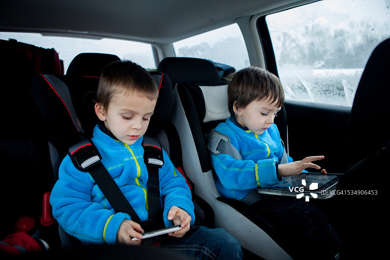 两个孩子坐在汽车座椅上，在车里旅行，玩耍图片素材