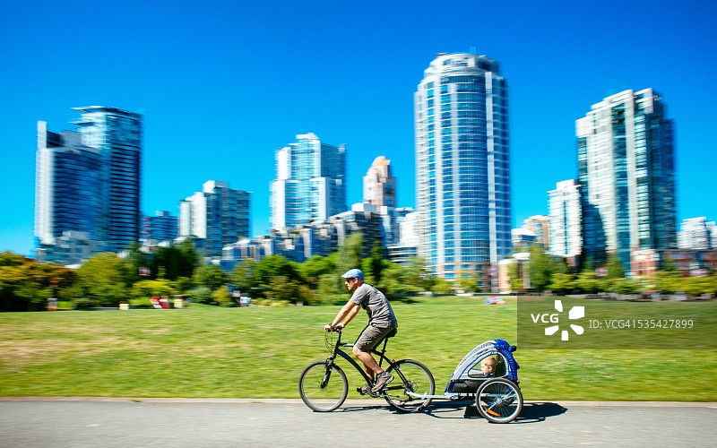 在加拿大温哥华，父亲背着儿子在自行车拖车里图片素材