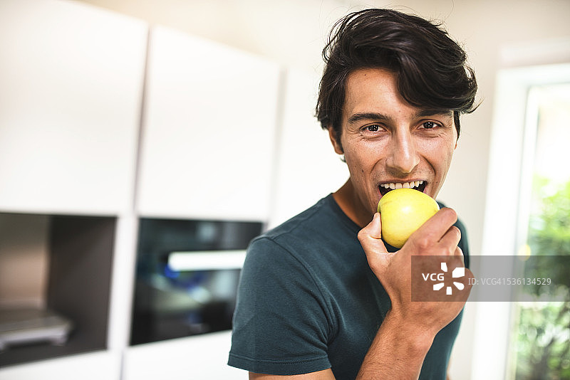 快乐的人在厨房吃苹果图片素材