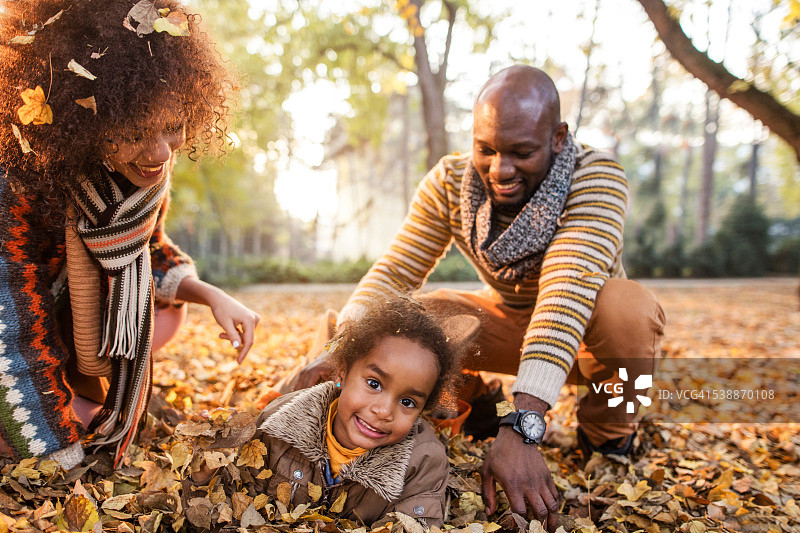 非裔美国小女孩与父母在秋天的乐趣。图片素材
