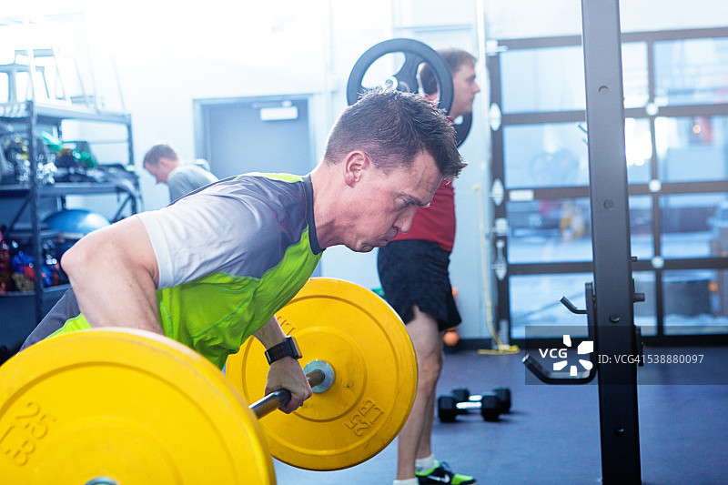 在健身俱乐部设施中锻炼举重的男人图片素材
