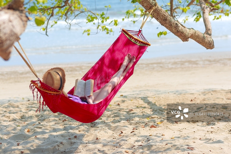 年轻女子在海滩上的吊床上放松图片素材