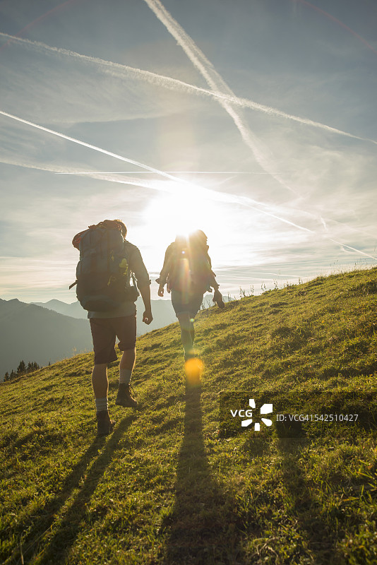 奥地利，蒂罗尔，坦海默·塔尔，一对在高山草地上徒步旅行的年轻夫妇图片素材
