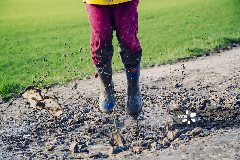 一个孩子在泥泞的水坑里跳图片素材
