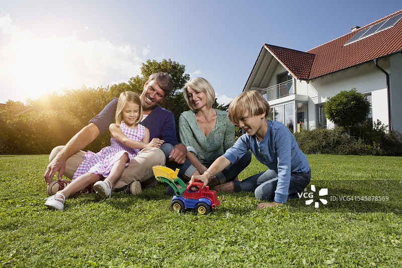 幸福的一家人坐在花园的草坪上图片素材