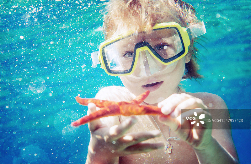 孩子抱着海星，水下观图片素材