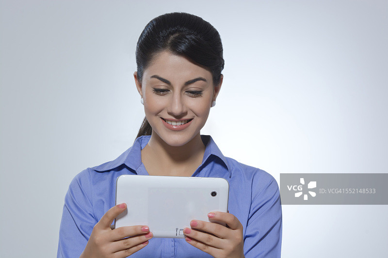 微笑的年轻女商人在灰色背景下使用数码平板电脑图片素材