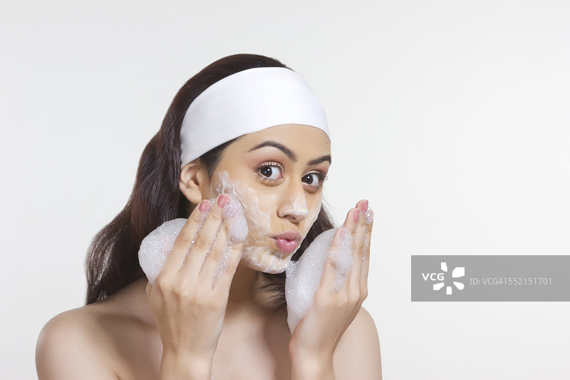 美丽的女人用肥皂擦洗脸的肖像白色的背景图片素材