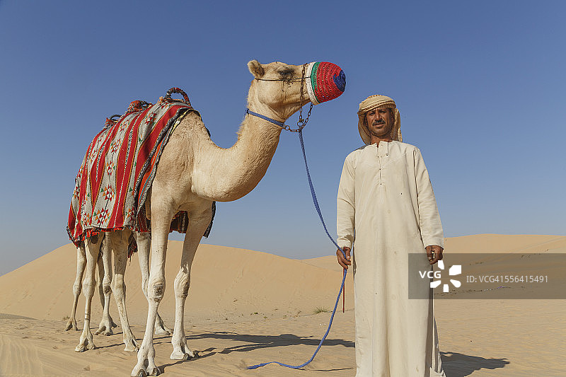 阿拉伯联合酋长国迪拜沙漠中贝都因人与骆驼的肖像图片素材