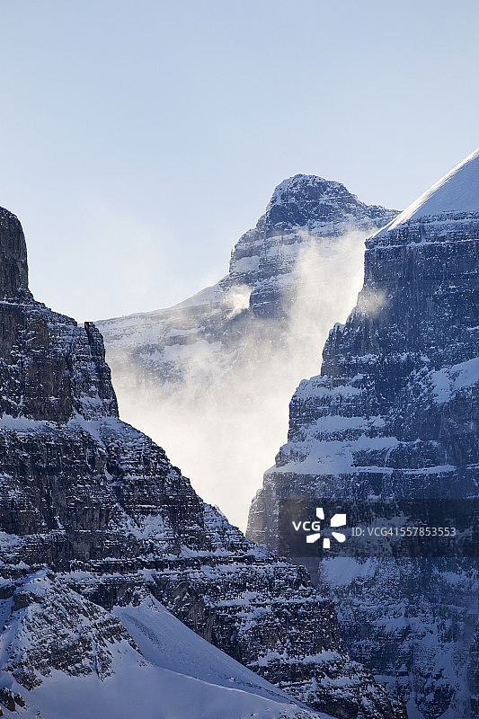 阳光下的雪吹过山顶，在一个v形的岩壁与蓝天图片素材