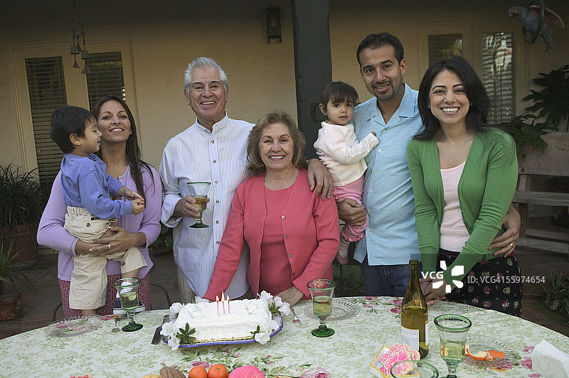 一个家庭在生日聚会上站在蛋糕前的肖像图片素材