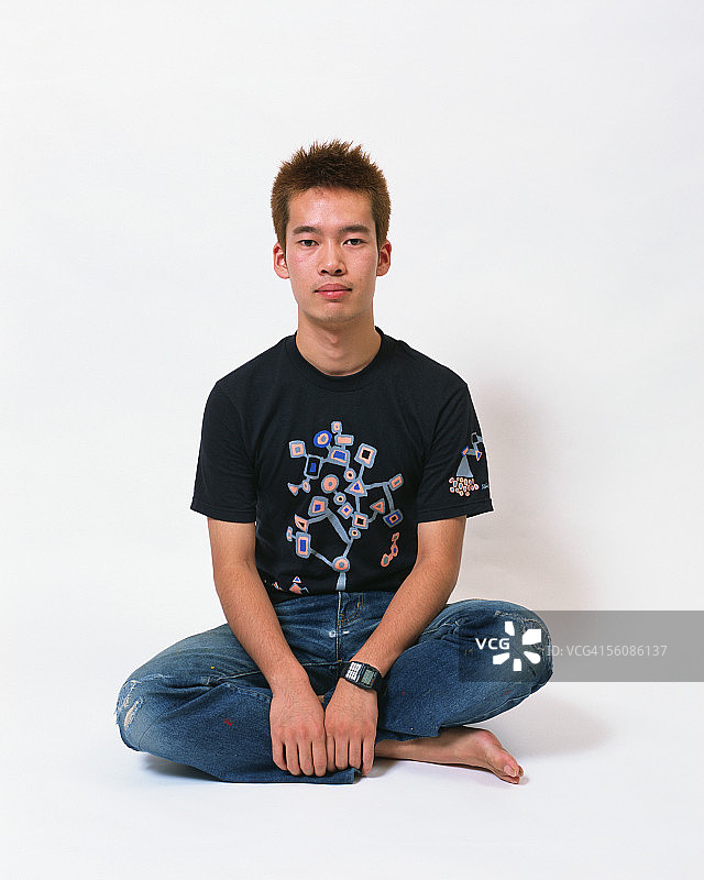 一个年轻人双腿交叉坐着的肖像图片素材
