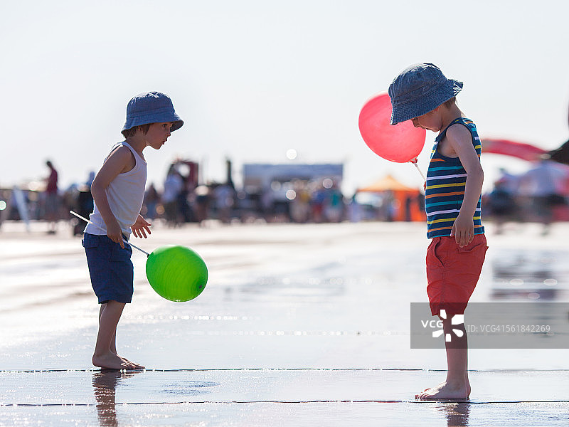 两个男孩，拿着气球，光着脚站着图片素材