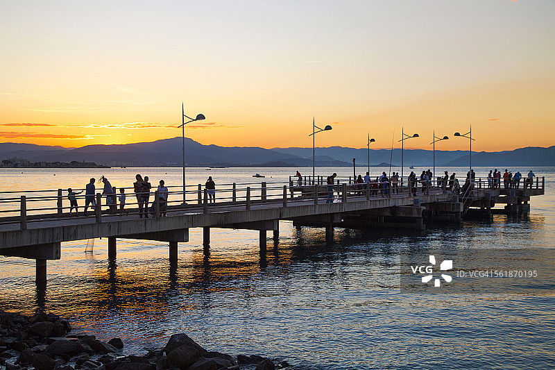 码头上的人们在凝望夕阳。图片素材
