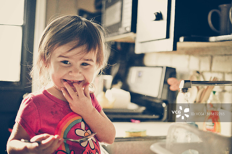 小女孩在厨房微笑。图片素材