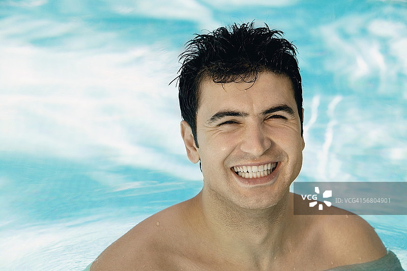 一个年轻男子在游泳池微笑的肖像图片素材