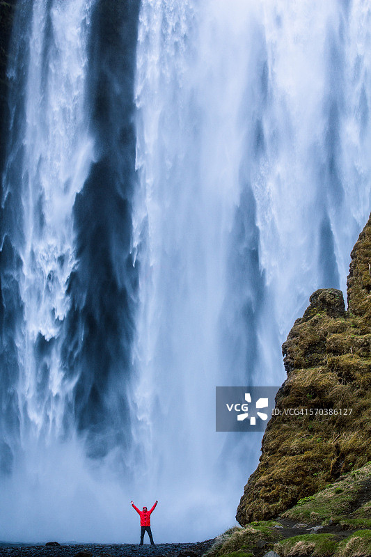 冰岛斯科加佛斯瀑布脚下，一名男子双手举在空中图片素材
