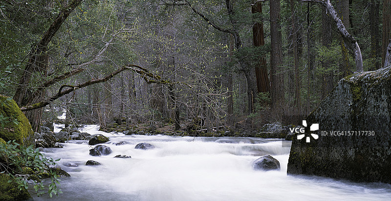 水流如瀑布般流过树木和巨石。快乐群岛，默塞德河，约塞米蒂国家公园，加利福尼亚州。图片素材