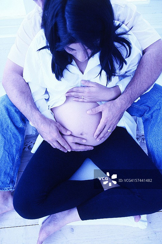 一个男人从后面抱着他怀孕妻子的肚子的高角度视图图片素材