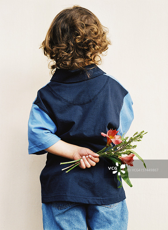 一个男孩(6-8岁)背后拿着花图片素材