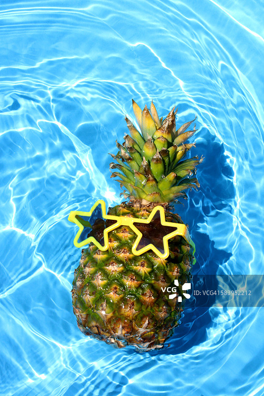 菠萝戴着太阳镜漂浮在游泳池里图片素材