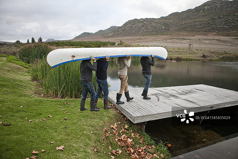 四个朋友带着独木舟来到湖边图片素材