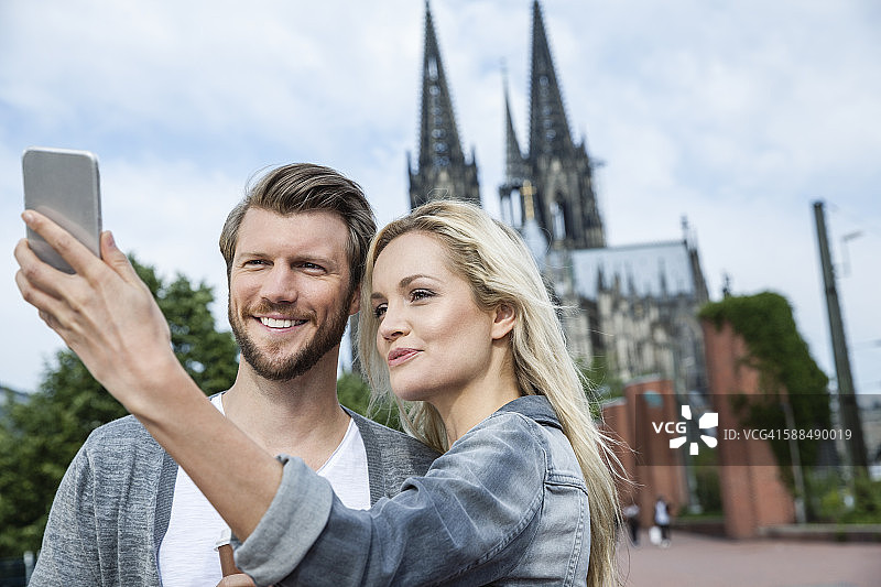 德国科隆，一对年轻夫妇用智能手机自拍图片素材