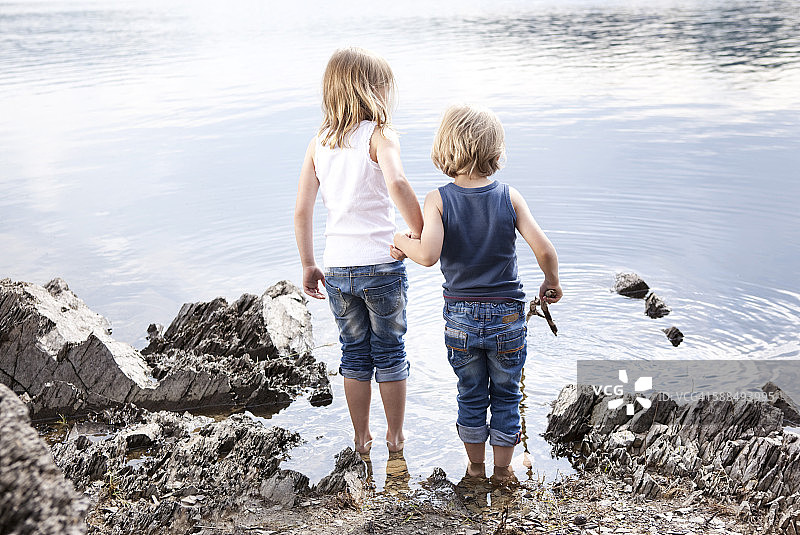 男孩和女孩手牵手站在湖边图片素材