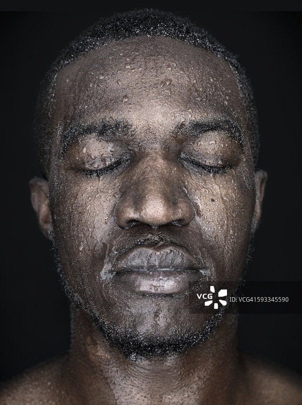 一个闭着眼睛，脸上有水滴的男人的肖像图片素材