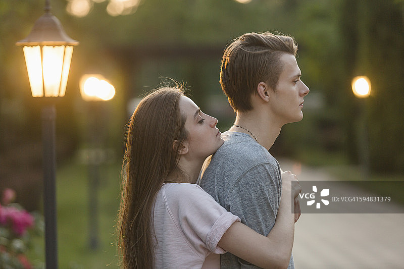 年轻女子在公园拥抱男友的侧视图图片素材
