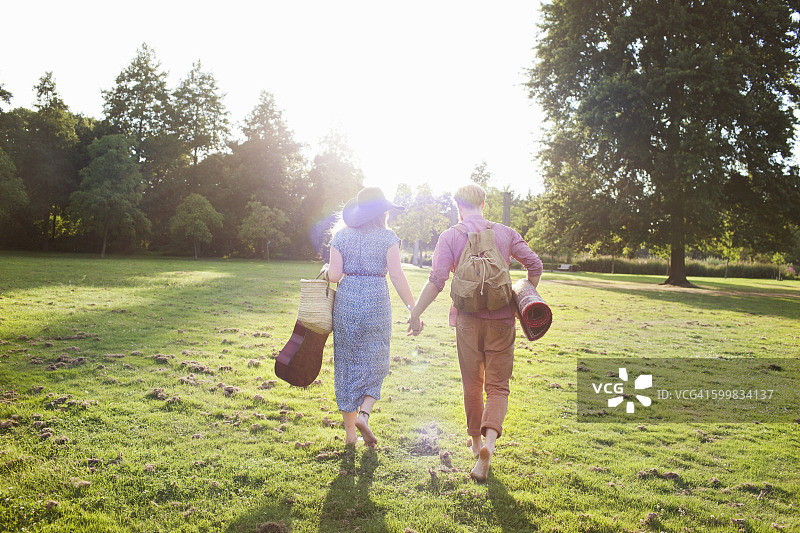 浪漫的年轻夫妇背着地毯在公园的后视图图片素材