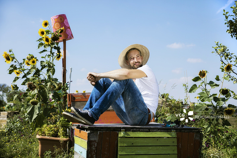 一个微笑的男人躺在花园里废弃的木桌上图片素材