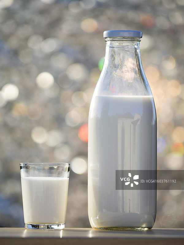 在阳光的照射下，桌子上放着玻璃和水晶牛奶瓶图片素材