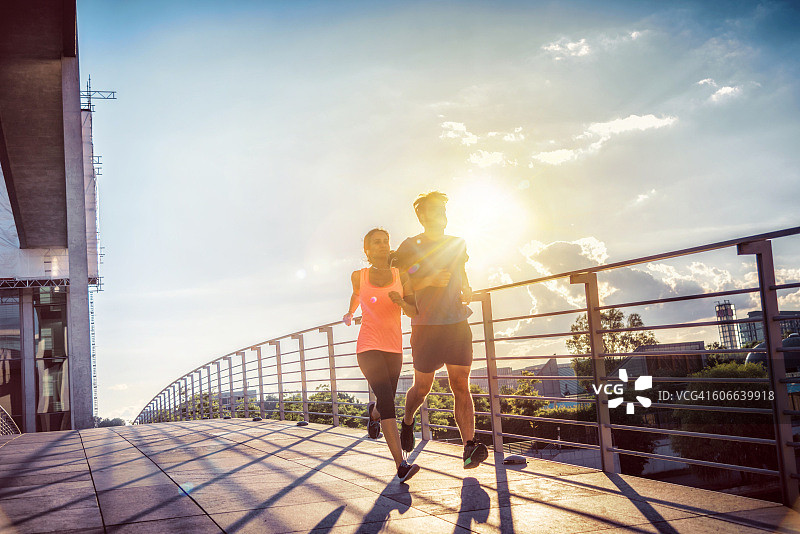 日落时分，女人和男人一起在柏林桥上慢跑图片素材