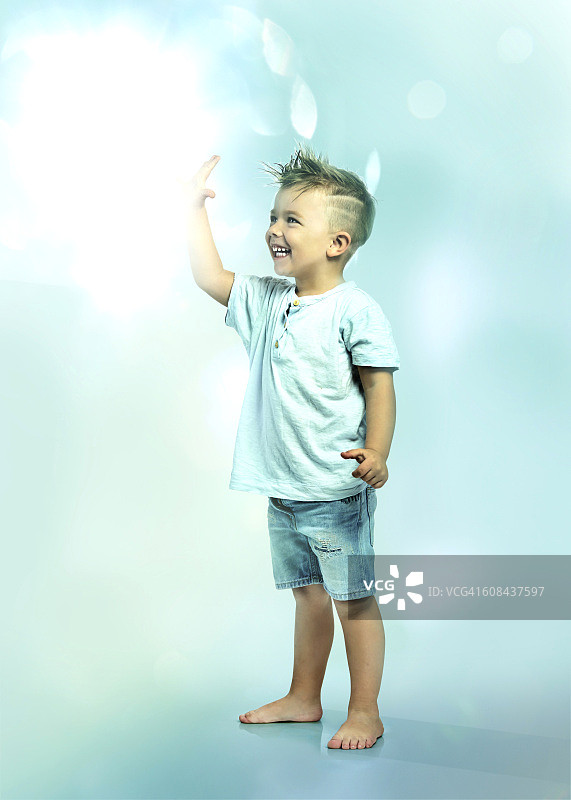 小男孩触摸着漂浮的光球图片素材