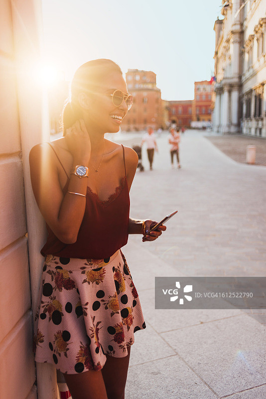 一名年轻女子在一个阳光明媚的日子里使用她的智能手机图片素材