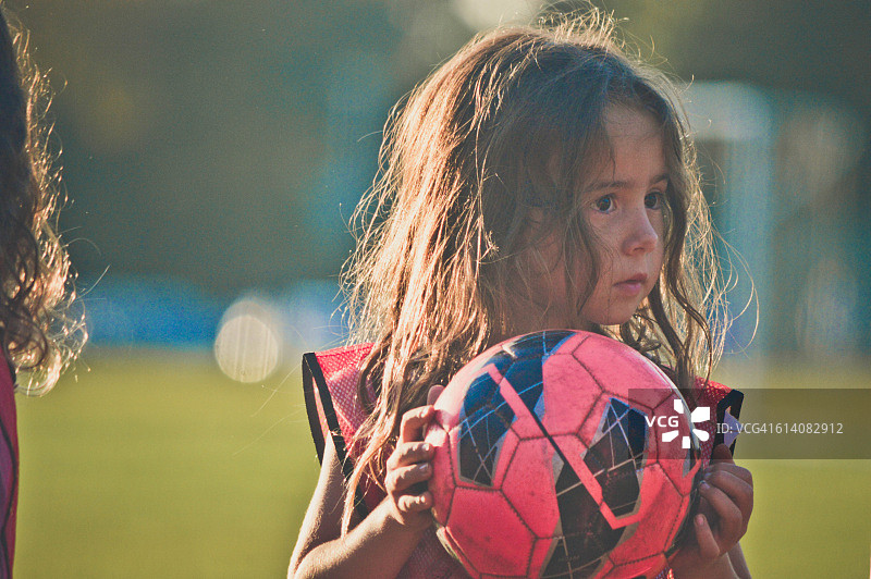 小女孩在踢足球。图片素材